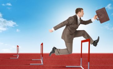Businessman hopping over treadmill barrier