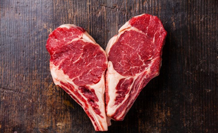 Heart shape Raw meat Ribeye steak entrecote on bone on wooden background